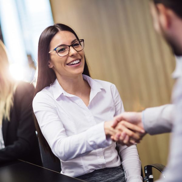 Smiling young business woman shaking hands